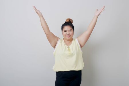 Beautiful plump Young Asian Woman smiling showing something with hands up isolated on white background textured for banner designの写真素材