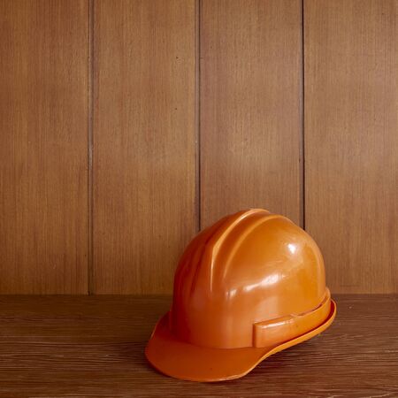 Orange Construction hard hat on wooden table background