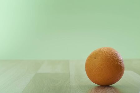 Fresh orange fruit on wooden table isolated on the green wall background, copy space for text