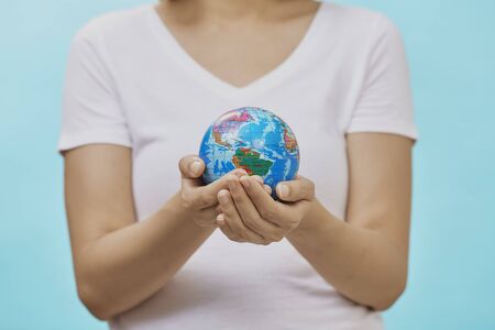 Woman holding Earth in hand on blue background. Safe world, safe people. copy space for textの写真素材