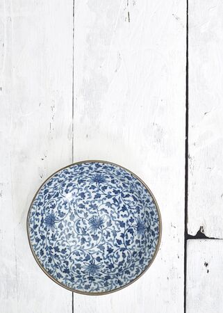 Flat lay Empty ordinary porcelain plate with blue patterns on white wooden tableの写真素材