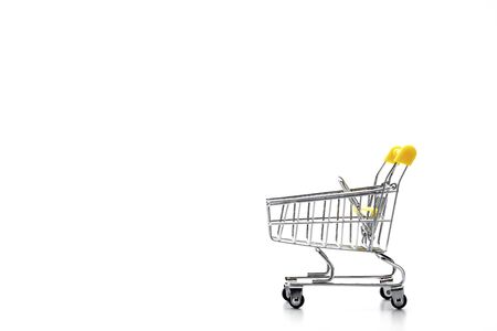 Empty toy metal supermarket shopping cart on white background with copy space, low angle side viewの写真素材
