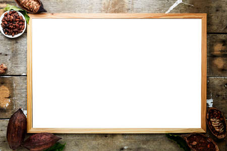 Dry cocoa pod with cocoa beans and cocoa powder with vintage picture frame on a wooden wall black...