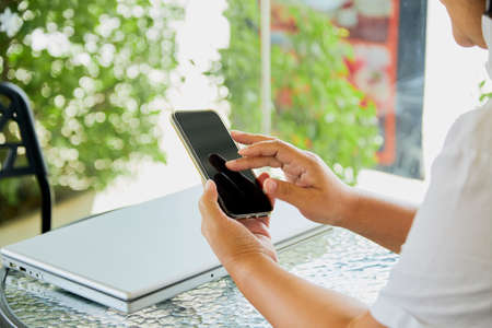 Asian woman sit using mobile smart phone and notebook in living room at home, Mock-up image...