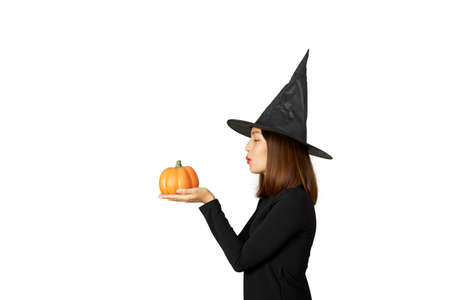 Halloween holiday background. Young pretty woman in witch hat holding halloween pumpkin jack o...
