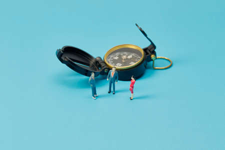 Miniature businessman and compass on bright blue backgrounの写真素材