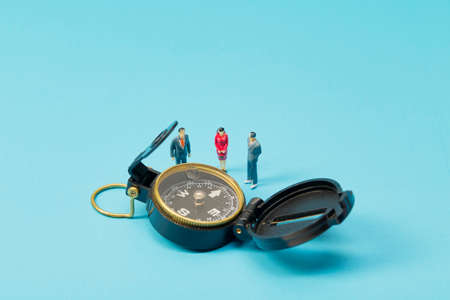 Miniature businessman and compass on bright blue backgrounの写真素材