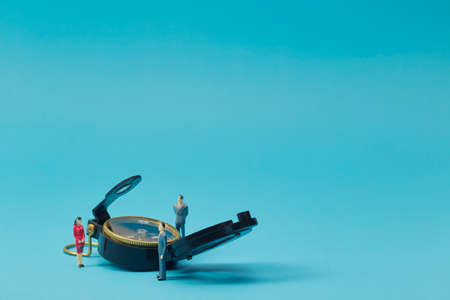 Miniature businessman and compass on bright blue backgrounの写真素材