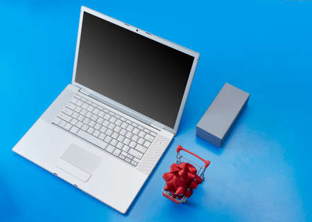 Top view Blank laptop with red bow in Shopping cart and blank gift box on violet background for Christmas Saleの写真素材