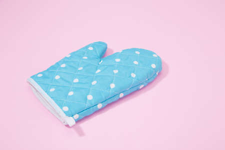 Blue dotted kitchen glove on isolated pink backgroundの写真素材