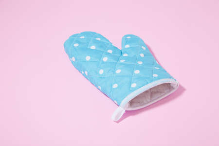 Blue dotted kitchen glove on isolated pink backgroundの写真素材
