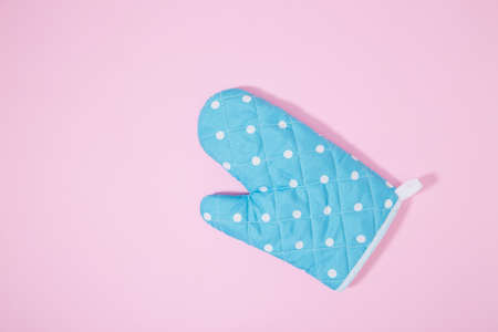 Blue dotted kitchen glove on isolated pink backgroundの写真素材