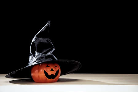 Jack O Lantern Halloween pumpkin with witches hat on wooden table with dark background copy space for textの写真素材