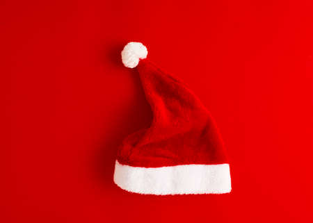 The minimalist concept of Christmas Santa Claus hat on red background flat lay top view