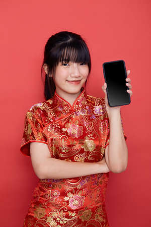 Portrait beautiful young Asian woman wear Chinese cheongsam use smart mobile phone for Mid-autumn festival concept on red isolated backgroundの写真素材