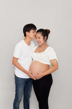 Asian lovely husband and wife portrait happy family expecting a baby  on white backgroundの写真素材