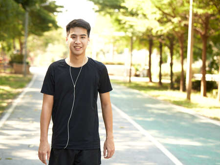 Young handsome Asian man exercising outdoors listening to music in the park.の写真素材