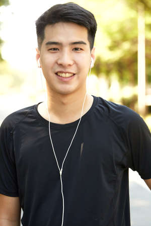 Young handsome Asian man exercising outdoors listening to music in the park.