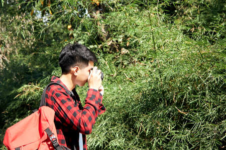 Young hipster Asian man traveling with a backpack in summer forest trip travel lifestyle concept