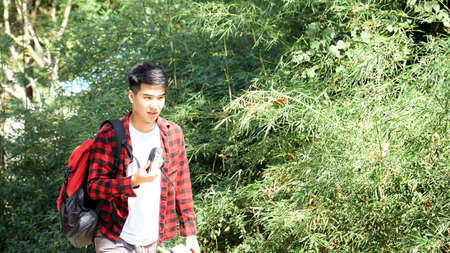 Young hipster Asian man traveling with a backpack in summer forest trip travel lifestyle concept