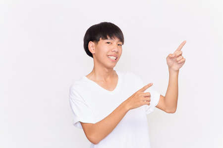 portrait of a young Asian man with hand point on empty space isolated on white backgroundの写真素材