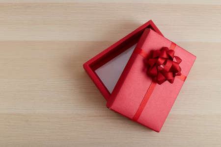 Red gift box with ribbon bow opened on vintage white wooden table Merry Christmas and Happy New Yearの写真素材