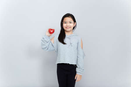 Portrait of a little girl holding a red heart Shape on gray background