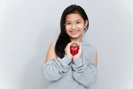Portrait of a little girl holding a red heart Shape on gray backgroundの写真素材