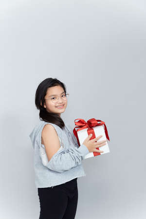 beautiful little girl with a gift and happy emotions on a gray background, a gift for the new year, March 8, Valentine's Day, mother's dayの写真素材