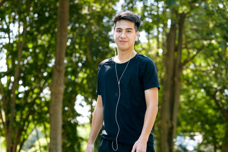 A young Asian happy cheerful smiling man during morning jogging outdoors. Fitness, sport, exercising crossfit, and workout concept.の写真素材