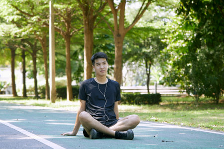 Young Man Sitting on the Floor After Training Outdoors in the parkの写真素材