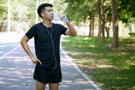 A man standing for a break from exercise with a water bottle in the park