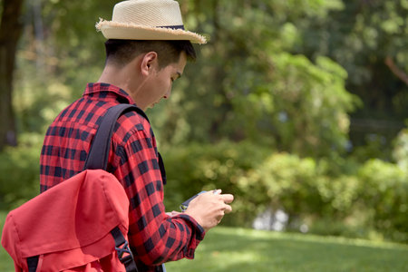 A handsome young Happy tourist man carrying a backpack in the green forestの写真素材