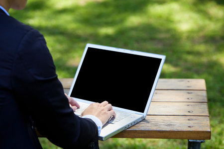 Back view of a young businessman sitting in the garden for workの写真素材