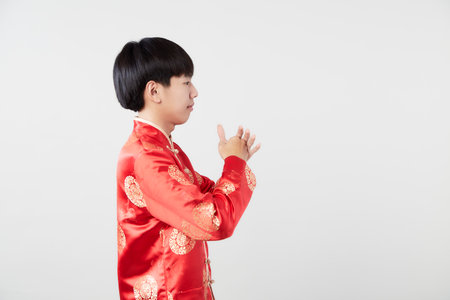 happy Chinese new year young Asian man with a gesture of congratulation in light gray isolated studio backgroundの写真素材