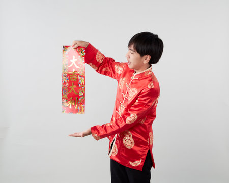 Asian man in traditional oriental costume holding couplet the Chinese word means congratulations and best wishes for a prosperous on light gray background for Chinese new year conceptsの写真素材