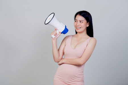 Happy beautiful Asian woman talking on magaphone isolated  on light gray background with copy spaceの写真素材