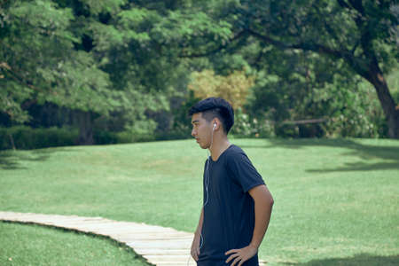 young handsome Asian exercising in the park wearing a fitness trackerの写真素材