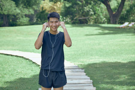 young handsome Asian exercising in the park wearing a fitness trackerの写真素材