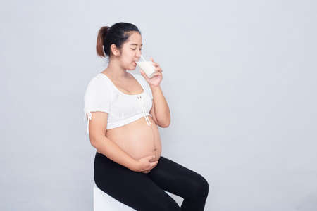 Healthy Calcium Drink. Pregnant young asian woman sitting Healthy Calcium Drink. Pregnant young Asian woman sitting holding a glass of milkの写真素材