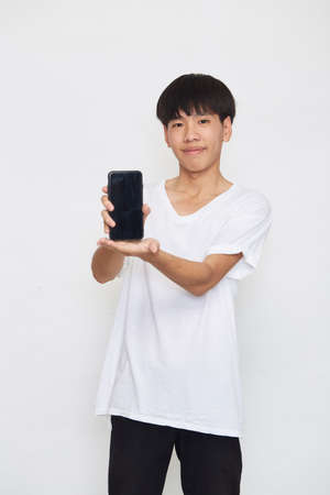 Handsome Young Asian man student texting messages using smartphone on a light background. Copy space and mockupの写真素材
