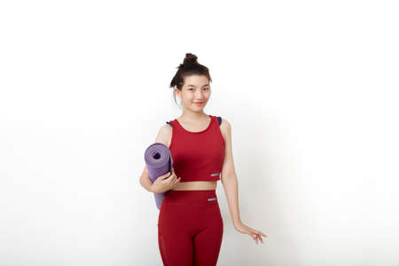 exercise fitness Thai Asian woman ready for workout standing holding yoga mat on white backgroundの写真素材