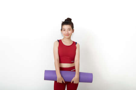 exercise fitness Thai Asian woman ready for workout standing holding yoga mat on white backgroundの写真素材