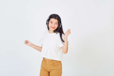 Young Asian woman with headphones and dancing on white backgroundの写真素材