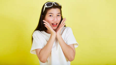 Young beautiful Asian woman smiling and pointing isolated yellow bright color backgroundの写真素材