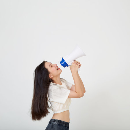 cheerful young Asian woman holding megaphone  announcement in isolated studioの写真素材