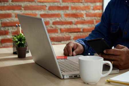 Online shopping concept, Close up young man using mobile smartphone and credit card making online payment with laptop computer on the tableの写真素材