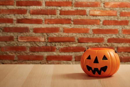 spooky Halloween pumpkin, Jack O Lantern on a wooden bench table, and brick wall copy space for textの写真素材