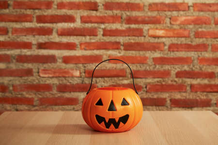 spooky Halloween pumpkin, Jack O Lantern on a wooden bench table, and brick wall copy space for textの写真素材