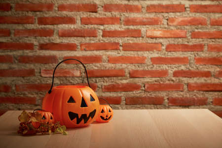 spooky Halloween pumpkin, Jack O Lantern on a wooden bench table, and brick wall copy space for textの写真素材